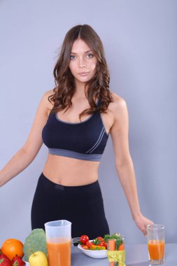 Sebzelerle masanın yanında duran genç ve güzel bir kadın..