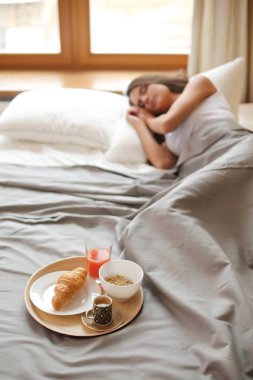 bir bardak süt ile yatakta oturan genç kadın