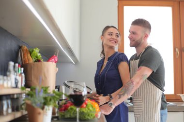 Bir çift evdeki mutfaklarında birlikte yemek pişiriyor.