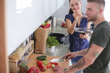Bir çift evdeki mutfaklarında birlikte yemek pişiriyor.
