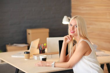 Moda tasarımcıları stüdyoda çalışıyor. Masanın üzerinde oturuyorlar..