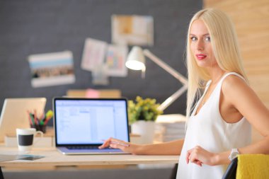 Moda tasarımcıları stüdyoda çalışıyor. Masanın üzerinde oturuyorlar..