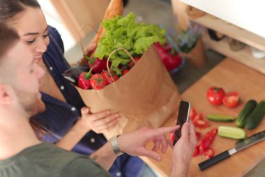 Mutlu çift Smartphone ayakta mutfakta kullanarak