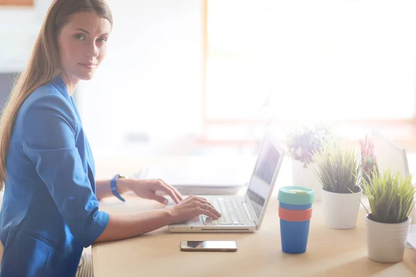 Donna seduta sulla scrivania con computer portatile. — Foto Stock