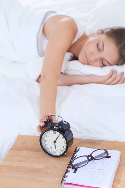 Una mujer joven apagando su despertador por la mañana. — Foto de Stock