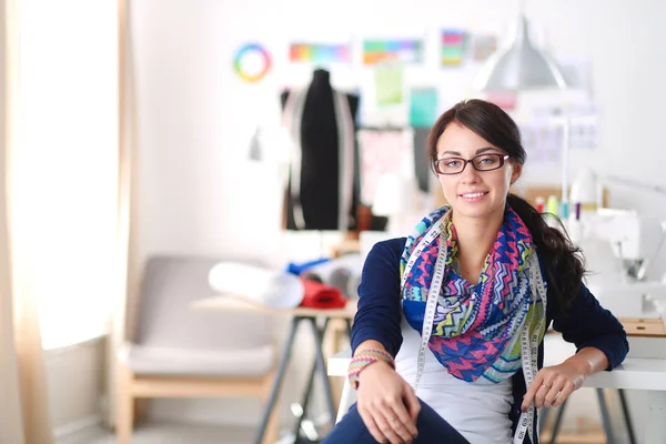 Hermoso diseñador de moda sentado en el escritorio en el estudio . — Foto de Stock