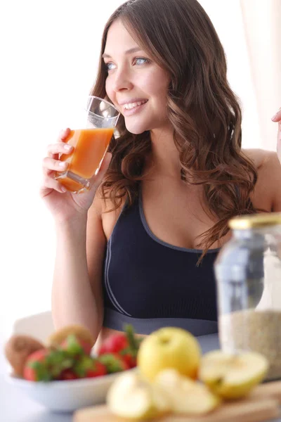 Flicka sitter i köket på skrivbord med frukt och glas med juice. — Stockfoto