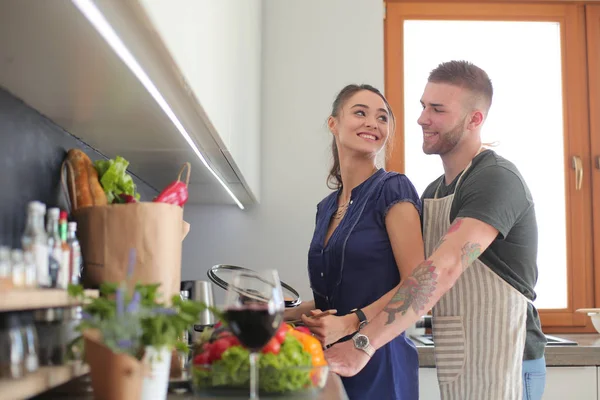 Bir çift evdeki mutfaklarında birlikte yemek pişiriyor.