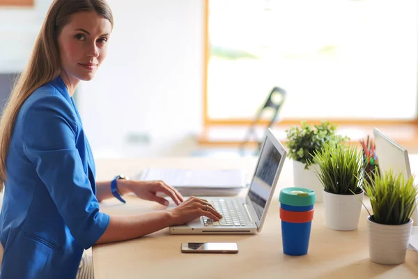 Kvinna sitter på skrivbordet med bärbar dator. — Stockfoto