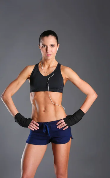 Musculosa joven posando en ropa deportiva sobre fondo negro . — Foto de Stock