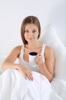 Genç ve güzel bir kadın yatakta oturuyordu .