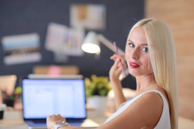 Moda tasarımcıları stüdyoda çalışıyor. Masanın üzerinde oturuyorlar..