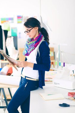 Güzel moda tasarımcısı stüdyoda duruyor. .