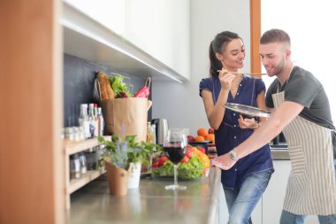 Bir çift evdeki mutfaklarında birlikte yemek pişiriyor.