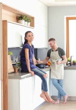 Bir çift evdeki mutfaklarında birlikte yemek pişiriyor.