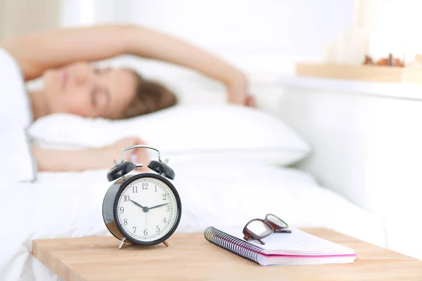 A young woman putting her alarm clock off in the morning. — Stock Photo, Image