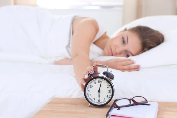 Una mujer joven apagando su despertador por la mañana. — Foto de Stock