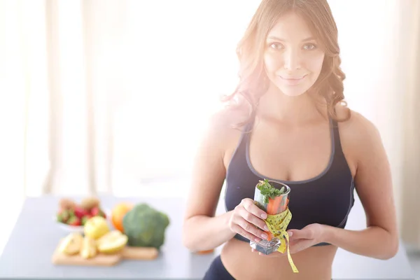 Kvinna som håller ett dricksglas fullt av färsk fruktsallad med ett måttband runt glaset. — Stockfoto