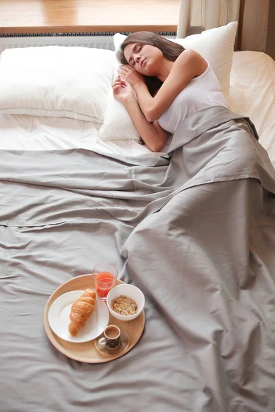 bir bardak süt ile yatakta oturan genç kadın