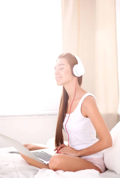 Jonge mooie vrouw in bed luisteren naar muziek. — Stockfoto