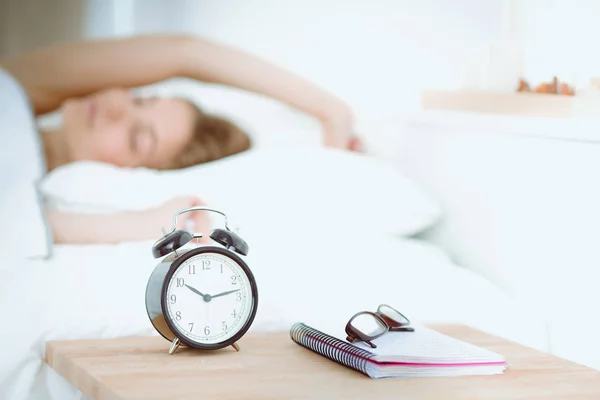 En ung kvinna stänger av väckarklockan på morgonen.. — Stockfoto