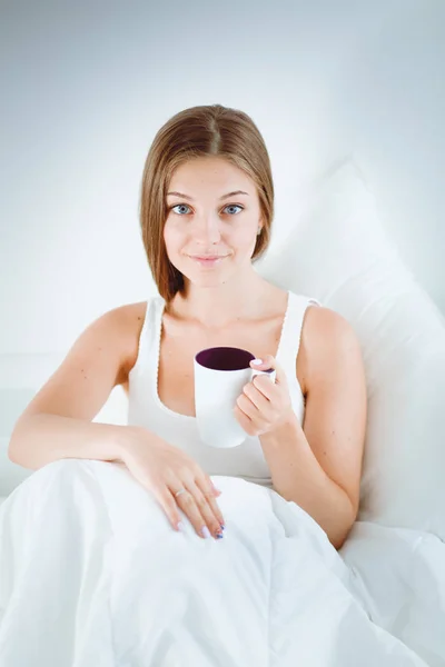 A pretty young woman sitting in bed . — Stock Photo, Image