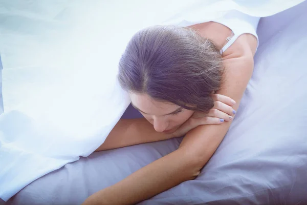 Young woman sitting in bed with a cup of milk — Stock Photo, Image