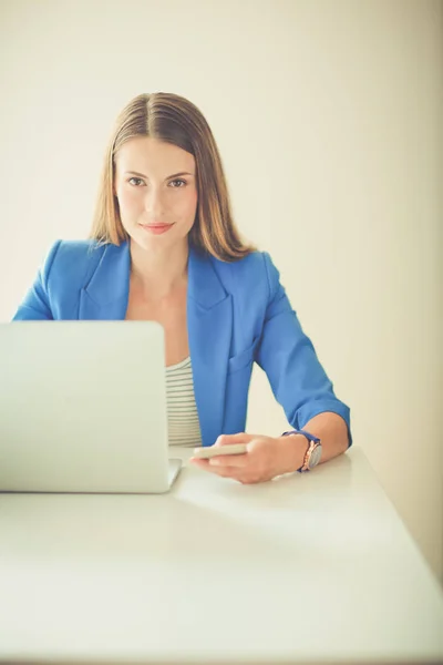 Portret van een jonge vrouw op telefoon achter een laptopcomputer — Stockfoto