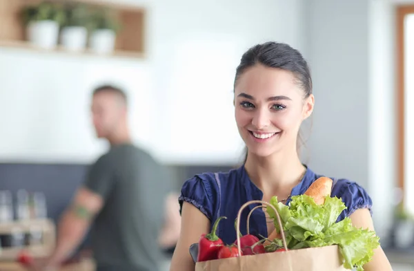 Unga par i köket, kvinna med en påse livsmedel shopping — Stockfoto