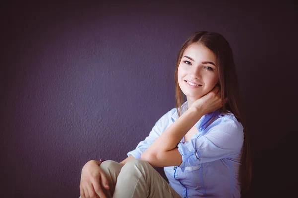 Young woman sitting on the floor near dark wall — Stock Photo, Image