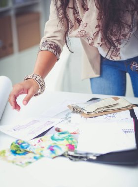 Gülümseyen kadın moda tasarımcısı ofis masasında oturuyor.