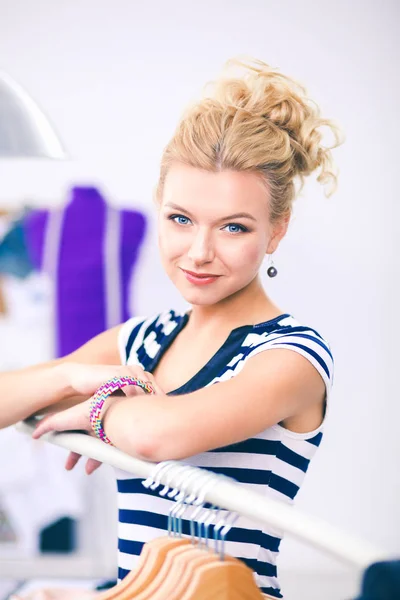 Beautiful young stylist woman near rack with hangers — Stock Photo, Image