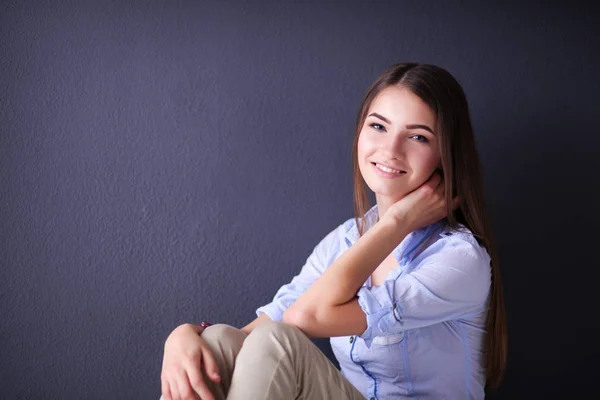 暗い壁の近くの床に座っている若い女性 — ストック写真