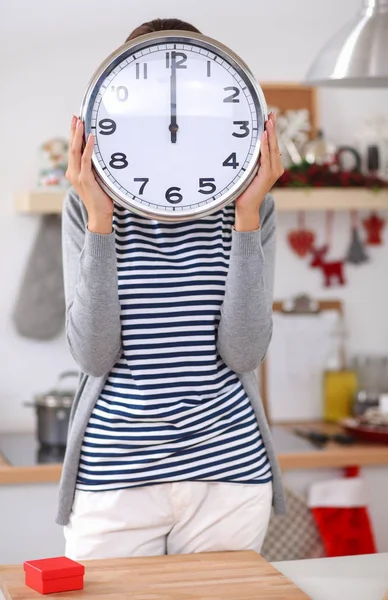 Happy young woman showing clock in christmas decorated kitchen — Stock Photo, Image