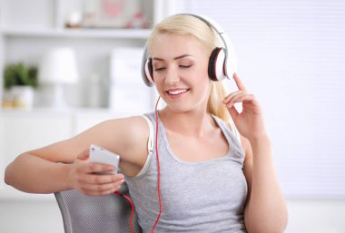 Evdeki genç ve güzel kadın kanepede oturup müzik dinliyor.