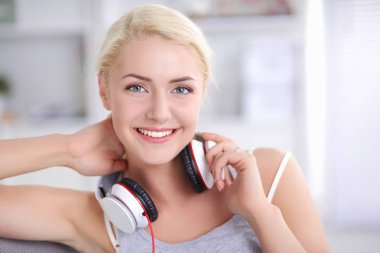 Evdeki genç ve güzel kadın kanepede oturup müzik dinliyor.