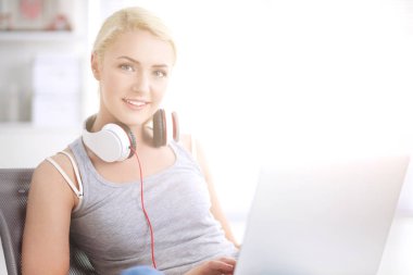 Evdeki genç ve güzel kadın kanepede oturup müzik dinliyor.