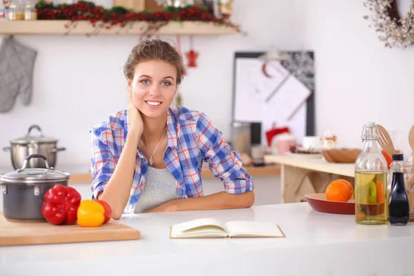 Jovem mulher sentada uma mesa na cozinha — Fotografia de Stock