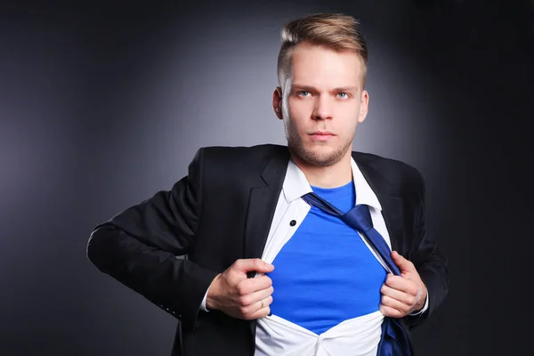 Young businessman acting like a super hero and tearing his shirt, isolated on gray background — Stock Photo, Image