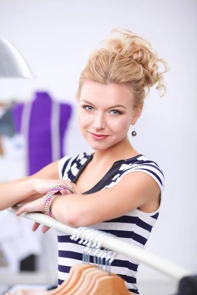 Piękny stylista młoda kobieta w pobliżu stojak z wieszakami — Zdjęcie stockowe