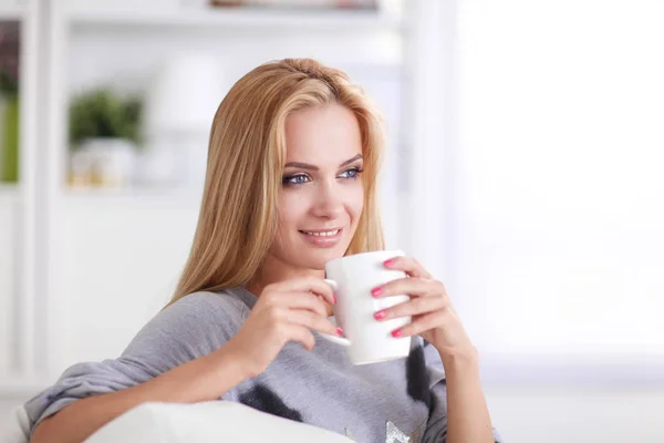 Giovane donna che riposa sul divano e beve tè nella stanza della luce — Foto Stock