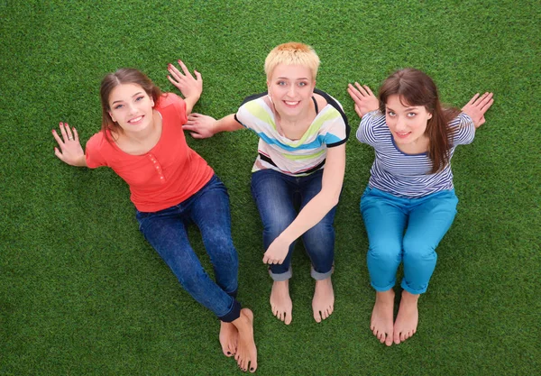 Tres relajantes hermosas mujeres coqueteando se sientan en la hierba verde — Foto de Stock