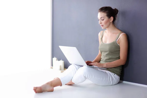 Attraktiva kaukasiska flicka sitter på golvet med laptop — Stockfoto