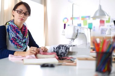 Genç terzi kâğıt üzerinde kıyafet deseni tasarlıyor. .