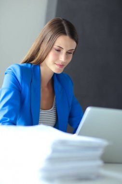 Elinde evrakları olan kadın masanın üstünde oturuyor.