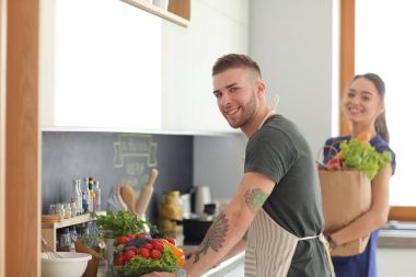 Bir çift evdeki mutfaklarında birlikte yemek pişiriyor.