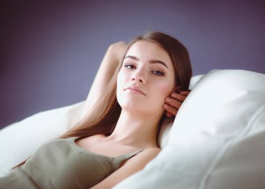 Kanepede uzanmış gülümseyen genç bir kadının yakın çekimi.