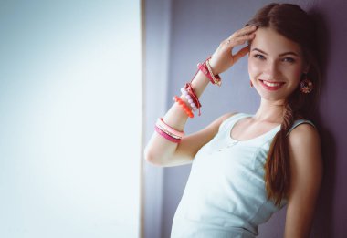 Gri arka plan üzerinde duran çekici genç kadın