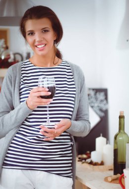 Güzel kadın mutfakta şarap içiyor.