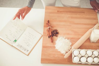 Mutlu genç kadın Noel süslemeli mutfakta saat gösteriyor.